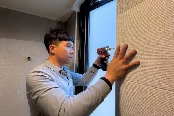 民輝門窗師傅在高雄修門窗換玻璃，幫浴室推開窗安裝定位卷軸，開窗時才有紗網能擋蚊子